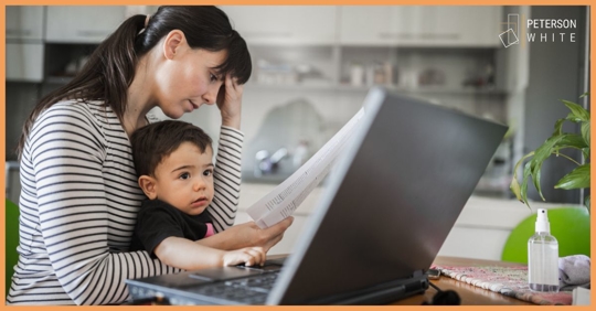 Mother looking at bills with her young child nearby